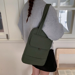 Olive green quilted crossbody bag shown in a cozy home setting with laptop storage space