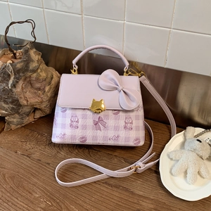 Detail of light purple square bag with oversized bow and golden cat-shaped metal clasp