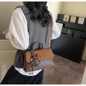 Detail of retro brown patchwork handbag with woven texture and gold metal buckle