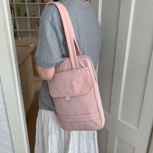 Side view of pink quilted nylon shoulder bag with front flap pocket on a female model