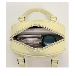 Top view of cream yellow mini Boston bag showing internal storage for cosmetics