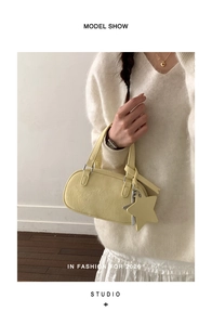 Detail shot of a light yellow Boston bag with leather texture and star charm accessory