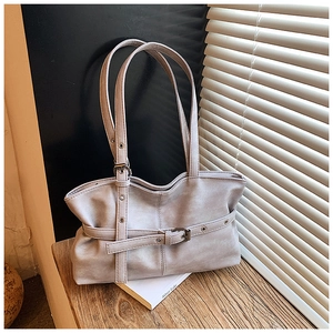 Détail d'un sac à bandoulière plissé gris clair avec boucle de ceinture sur une table en bois