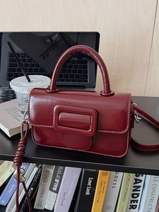 Minimalist burgundy leather crossbody bag with iconic square buckle and top handle
