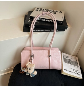 Close-up of pink matte shoulder bag featuring silver buckle and cute teddy bear charm