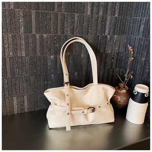Détail du sac à bandoulière plissé crème avec boucles de ceinture et œillets métalliques