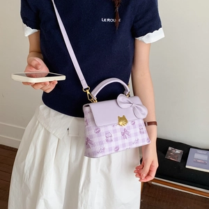 Detail of light purple square bag featuring gold cat buckle and decorative bow