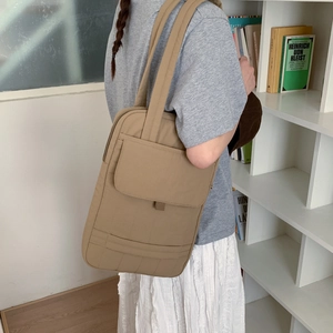 Close-up of minimalist khaki nylon crossbody bag showing the front pocket and sturdy strap