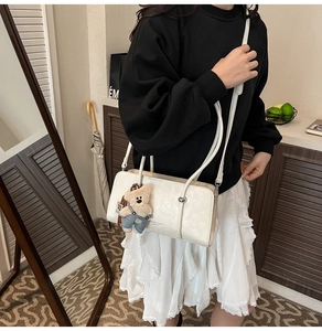 Detail of white rectangular shoulder bag with Fashion & Bags print and cute bear charm