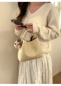 Detail view of beige bucket bag with cute bear charm and polka dot bow accessory