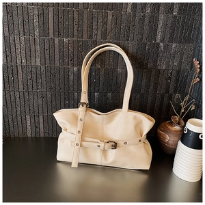 Détail d'un sac en similicuir plissé crème avec boucle décorative sur fond de pierre grise