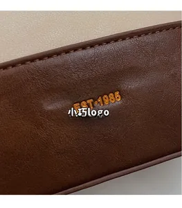 Dettaglio pelle a grana con logo dorato stampato e cuciture di alta qualità