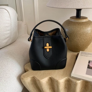 Detail of black pebbled leather bucket bag with gold cross-twist lock and textured handle