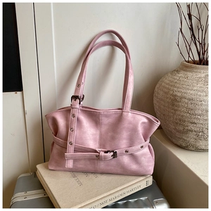 Gros plan du sac à bandoulière rose clair plissé avec œillets sur des livres