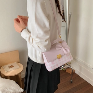 Close-up of pink square shoulder bag featuring a large bow and cat-shaped metal clasp