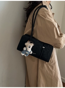 Detail of black matte shoulder bag with silver hardware and cute teddy bear charm