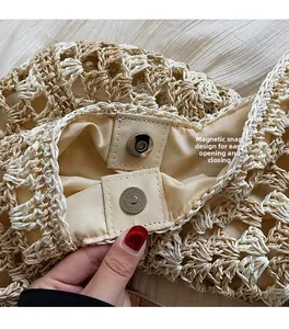Detail of magnetic buckle closure on a beige straw tote bag with woven texture