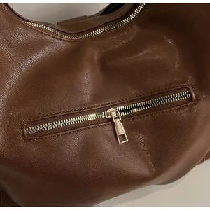 Close-up of high-quality smooth metal zipper and textured brown leather on handbag