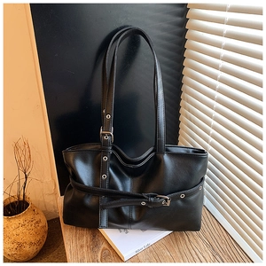Gros plan du sac cabas noir avec texture grainée, œillets métalliques et boucles argent