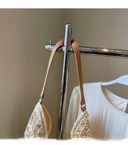 Detail of bohemian woven tote showing the ivory straw texture and brown leather strap