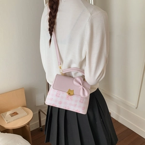 Pink crossbody bag with cat lock and bow detail shown on model from a side perspective