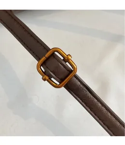 Detail of vintage brown leather strap featuring a high-quality gold metal buckle and stitching