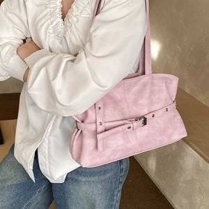 Gros plan d'un sac à bandoulière rose avec boucles à œillets et texture de cuir plissé rétro