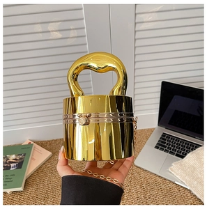 Primo piano di una borsa da sera cilindrica dorata con manico metallico dal design unico