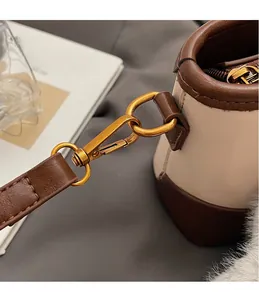 Dettaglio del gancio in metallo dorato e finiture in pelle marrone su borsa a secchiello