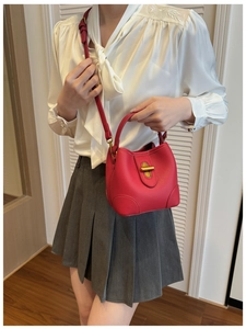 Detailed shot of a red leather bucket bag with gold clasp shown on a model