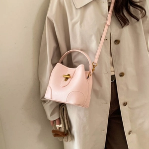 Elegant light pink bucket bag in litchi texture with gold twist lock and crossbody strap