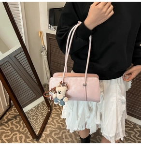 Detail of pink fashion handbag featuring a cute bear charm and thin shoulder strap
