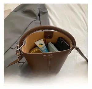 Vue détaillée de l'intérieur spacieux du sac seau marron avec les objets essentiels