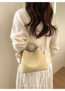 Chic cream-colored bucket bag with soft plush bear charm and detachable shoulder strap