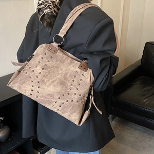Détail du sac bandoulière vintage marron avec clous métalliques et fini mat