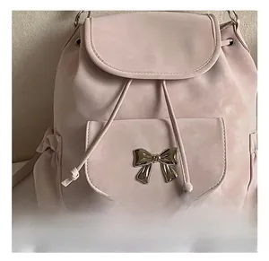 Détail du sac à dos en daim rose avec nœud métallique et fermeture à rabat coulissant