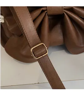 Detail of brown PU leather shoulder bag featuring bow pleated texture and golden buckle
