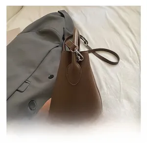 Gros plan du sac seau en cuir grainé marron avec détails de la ferronnerie argentée