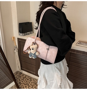 Detail view of pink rectangular shoulder bag with cute teddy bear charm and sleek straps