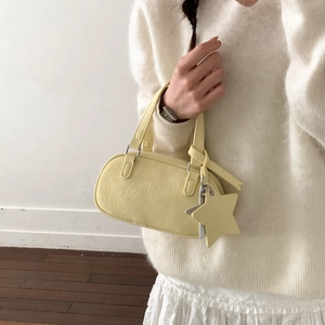Close-up of a pale yellow Boston bag featuring a removable star charm and silver hardware