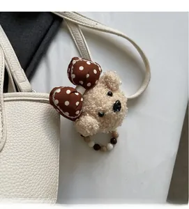 Detail of cute teddy bear charm with polka dot bow and colorful beads on leather handbag