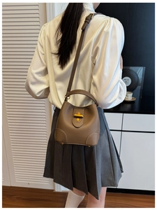 Brown lychee leather bucket bag with gold metal twist lock and versatile shoulder strap