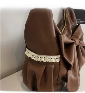 Detail of dark brown leather hobo bag featuring a large bow and beige lace trim