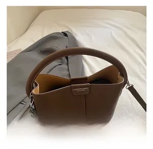 Vue détaillée du sac seau en cuir marron grainé avec boucle argentée sur fond blanc doux