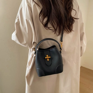 Detail of black pebbled leather bucket bag with gold twist lock and adjustable shoulder strap