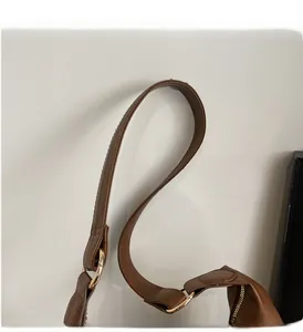 Detailed close-up of brown PU leather shoulder bag with gold metal rings and wide strap