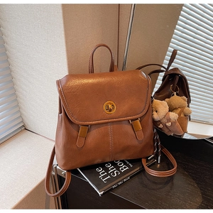 Detailed close-up of brown vintage PU leather backpack with gold round buckle and bear charm