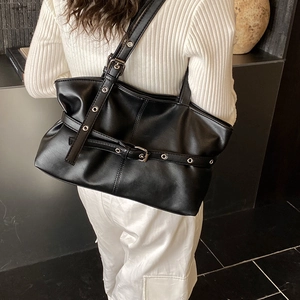 Détail d'un sac cabas en simili cuir noir avec œillets argentés et boucle de sangle