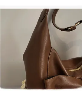 Close-up of litchi grain texture on brown faux leather bag with gold buckle hardware