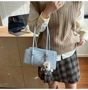 Detail of light blue rectangle shoulder bag with a cute white bear doll charm and thin straps